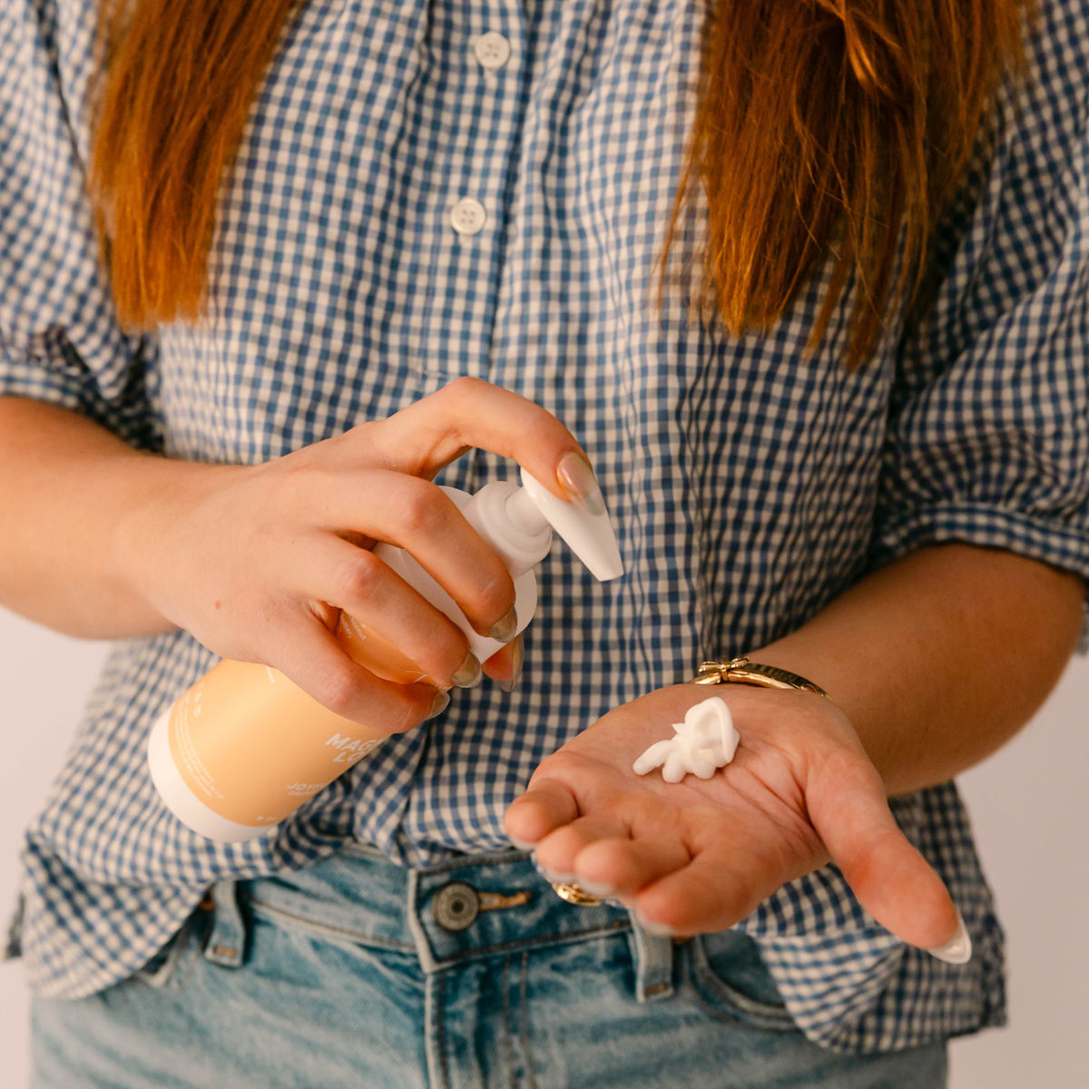 Woman dispensing Taylor Made Organics Joyful Citrus Magnesium Lotion into her palm.