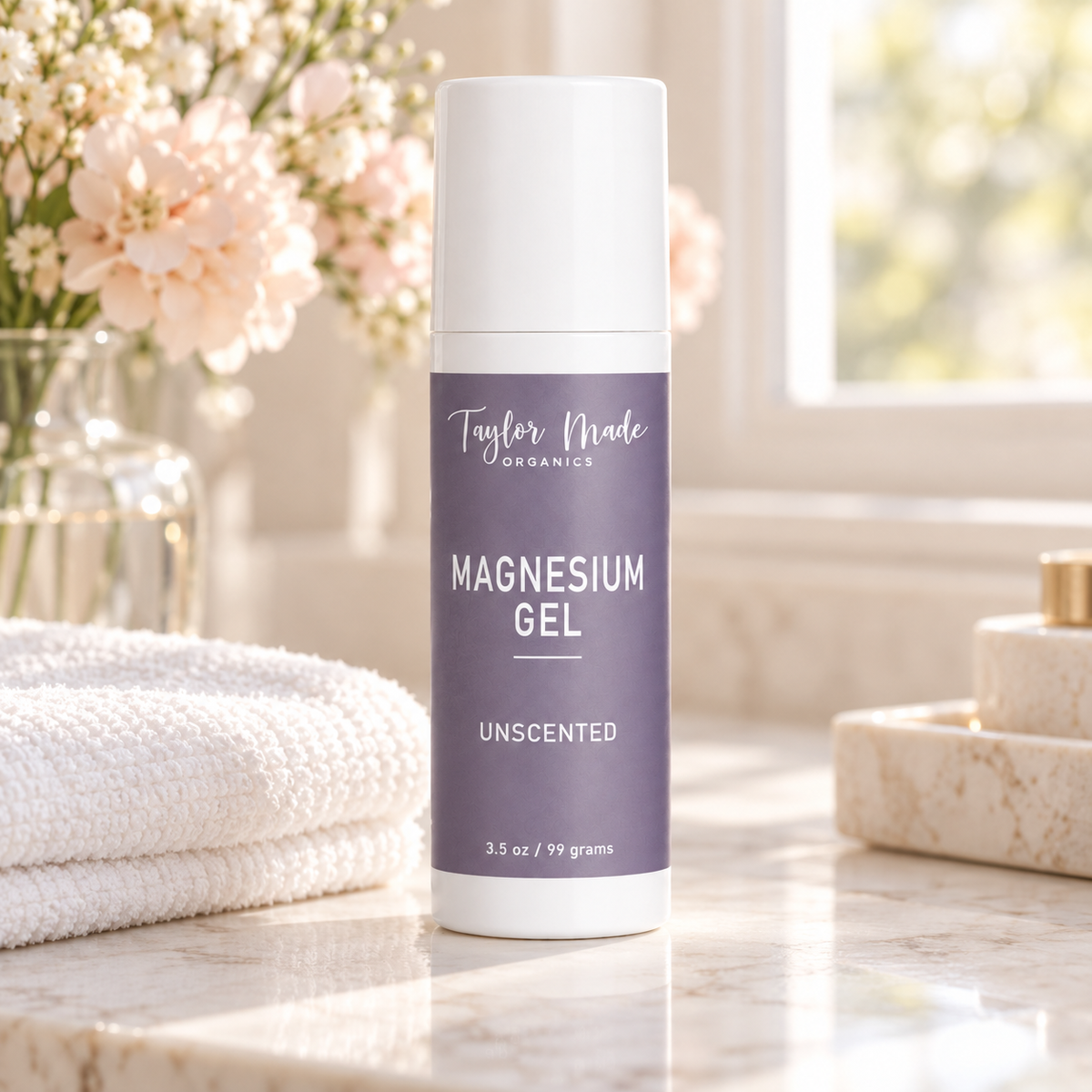 Taylor Made Organics Magnesium Gel unscented sitting on a granite countertop with a white towel and a vase filled with flowers. Made in the USA