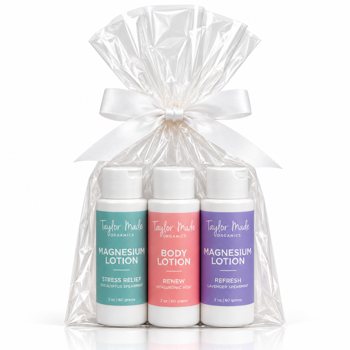 Taylor Made Organics Mindful Moments three-bottle lotion gift set of magnesium lotions in a clear cellophane bag tied with a white ribbon. The bottles feature teal, pink, and purple labels.