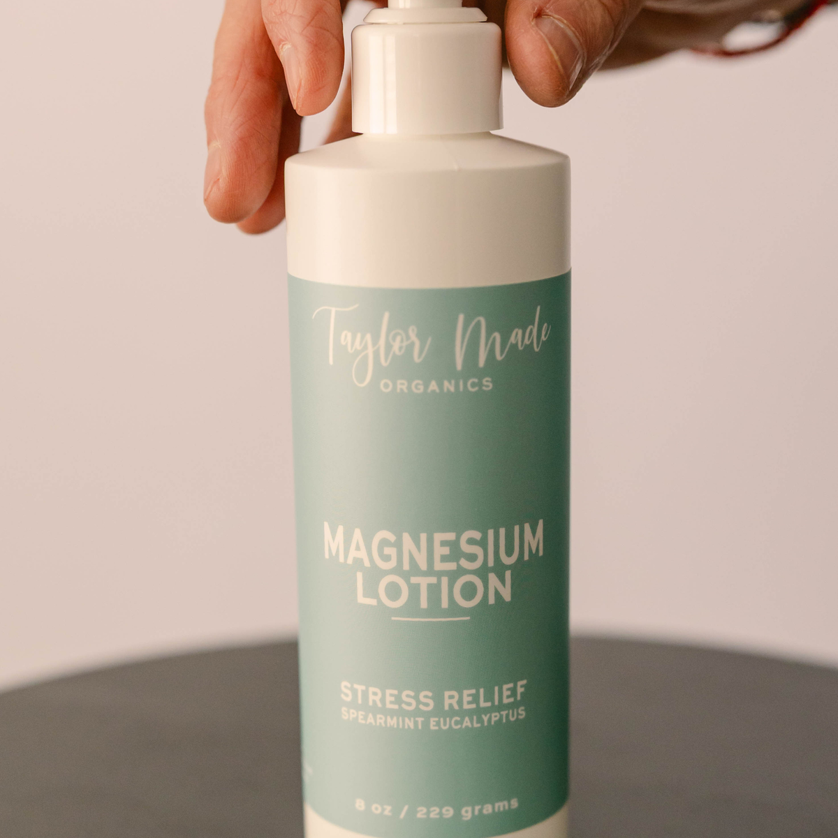Hand pressing the pump of Taylor Made Organics Stress Relief Magnesium Lotion with spearmint and eucalyptus.