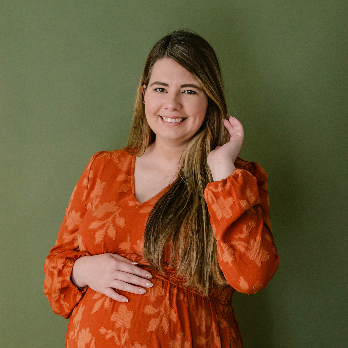 Pregnant woman wearing Taylor Made Organics Liquid Mineral Foundation, smiling against a green background.